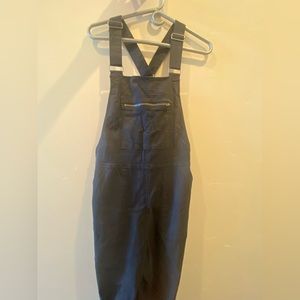 Black overalls with zippers at the hips and a pocket infront.